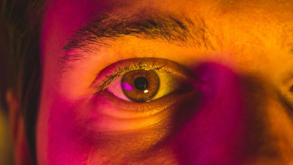 a close up of a man's eye with pink light
